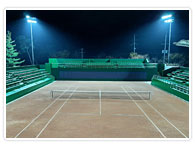 정면에서 바라본 야간 조명 아래 덕동시립테니스장의 주경기장 코트입니다.